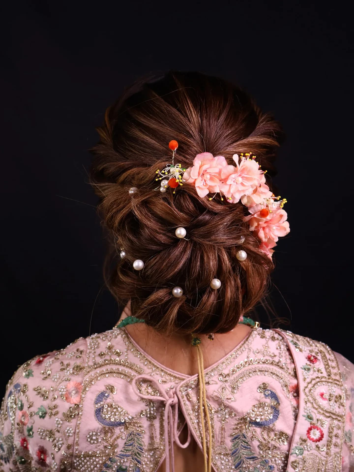 Bridal bun dressed with pearls and peach flowers
