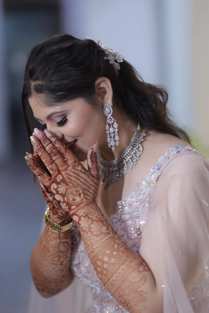 Bride smiling behind mehendi-covered hands