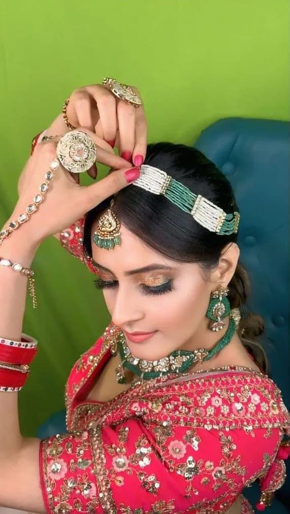 Bride in a red blouse with green beaded jewellery and a gold eye